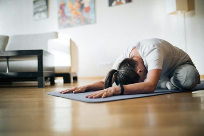 Mujer practicando yoga para principiantes en su casa.